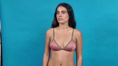 Bikini giyen genç bir kadın mavi arka planda farklı pozlar ve ifadeler gösteriyor.