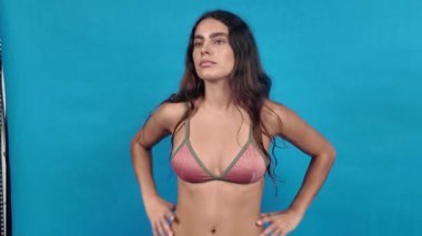 Moda modeli mavi arka planda farklı pozlar ve bikinili ifadeleri gösteriyor