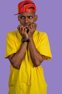 Mor arka planda tırnaklarını yiyen endişeli bir gencin stüdyo portresi.