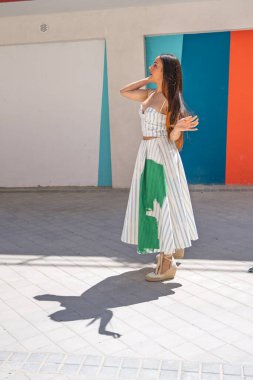 Şık bir model, canlı bir arkaplan karşısında yaz modasını sergiliyor, zarafet ve kendine güveni somutlaştırıyor.