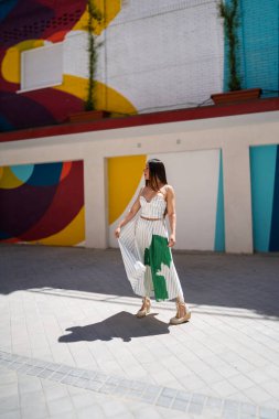 Şık bir model canlı bir şehir zeminine karşı yaz modası trendlerini sergiliyor