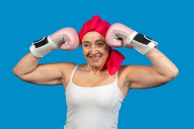 Mavi arka planda pembe boks eldiveni giyen gülümseyen son sınıf öğrencisi bir kadının portresi.