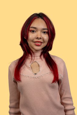 Sarı arka planda gülümseyen canlı kızıl saçlı bir kadın.