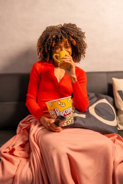 Evde sıcak bir akşam, patlamış mısır ve sıcak bir içecekle sinemanın keyfini çıkarıyorum.