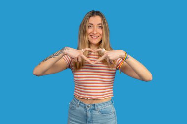 Elleriyle kalp şekli oluşturan gülümseyen genç kadın, lgbtq + topluluğuna destek veriyor