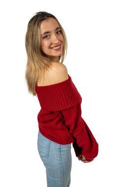 Kırmızı omuzlu süveter ve kot pantolon giyen, beyaz bir arka fonda poz veren neşeli genç bir kadının stüdyo fotoğrafı.