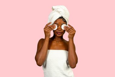 Güzellik modeli pamuk pedlerle makyaj yapıyor, cilt bakımının keyfini çıkarıyor.