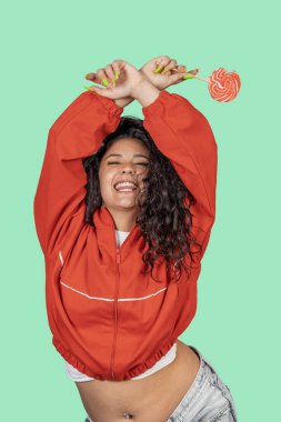 Tasasız genç bir kadın kollarını kaldırmış, gözleri kapalı yeşil arka planda büyük bir gülümsemeyle dans ediyor.