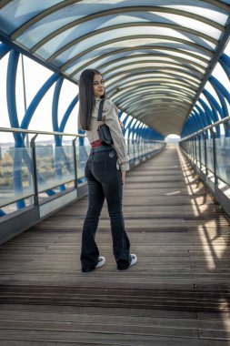 Modern köprünün üzerinde duran genç kadın arkasını kolluyor.