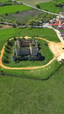 Havadan bakıldığında, İspanya 'nın kırsal kesimlerindeki yeşil tarlaların arasına yerleşmiş yıpranmış bir kalenin kalıntıları görülüyor.