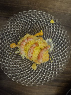 Karidesli Rus salatası ve rendelenmiş yumurta sarısı servis ederek ahşap bir masada kristal bir tabak süslüyor.