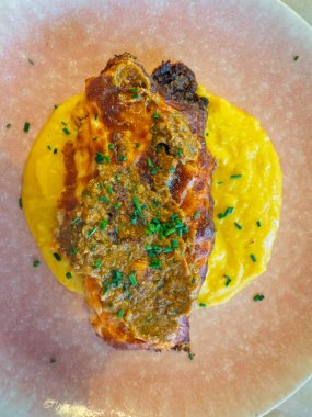 Bu kızarmış tavuk göğsüyle leziz bir mutfağın tadını çıkarın, canlı sosis ve kremalı patates püresi ile tamamlanmış, zarif pembe bir tabakta servis edilir.