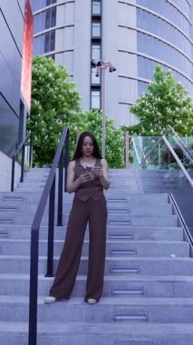 Modern bir şehirde merdivenlerde akıllı telefon kullanan bir iş kadını.