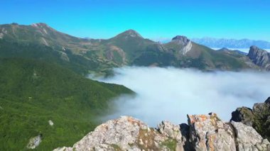Görkemli dağlar ve yeşil vadi mavi gökyüzünün altında kalın bir bulut tabakasıyla kaplıydı.