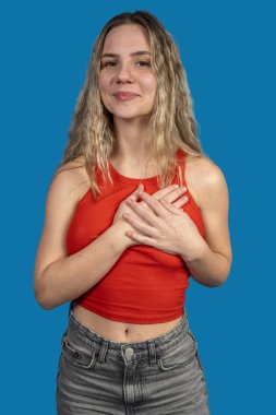 Minnettar genç bir kadının portresi göğsünde el ele tutuşarak mavi arka planda şükran ve umut gösteriyor.