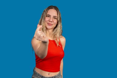 Gülümseyen sarışın bir kadının stüdyo portresi canlı mavi bir arka planda Kore 'nin aşk sembolünü gösteriyor.