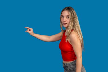 Genç bir kadın, mavi arka planda parmak uçlarını işaret ediyor.