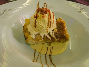 Vanilyalı dondurma, karamel sosu ve bir tutam çıtır çıtır soslu bir tabakta servis edilen ekmek pudingi.