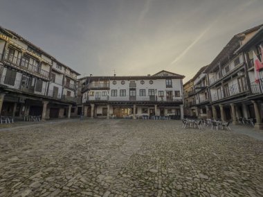 Geleneksel mimari, Candelario, Salamanca, İspanya 'daki kaldırım taşı meydanını sarar ve batan güneşin ılık parıltısıyla yıkanır.