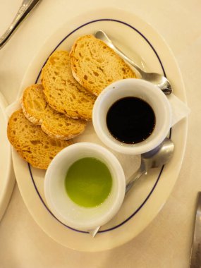 Zeytin yağı ve balzamik sirke sosuyla servis edilen çeşitli kızarmış ekmek dilimleri.