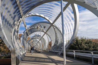 Modern Arganzuela yaya köprüsü boyunca eşsiz spiral metal yapısı ile yürüyen yayalar.