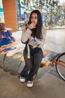 Benzersiz bir kaykay bankında oturan genç bir kadın şehir ortamında atıştırmanın tadını çıkarıyor.