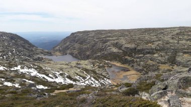 Dağlık engebeli arazinin geniş bir manzarası var. Kar, küçük göller ve bulutlu bir gökyüzü altında kayalık bir plato. Huzurlu doğanın ve doğal güzelliğin özünü yakalıyor..