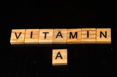 vitamin a - vitamin made of wooden blocks on black background. concept of vitamin