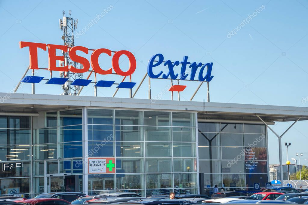 Glass-fronted supermarket entrance with Tesco Extra signage in bold red and blue letters atop the building.