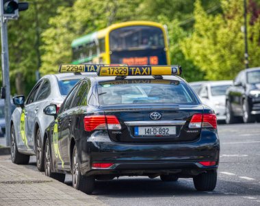 Sarı ve siyah çatısı ve damgalı siyah ve gümüş taksiler Dublin İrlanda 2025 'te bir sıra üzerine park edilmiştir...