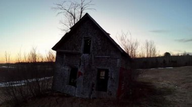 Gün batımından çok loş bir ışıkta terk edilmiş bir çiftlik evinin havadan görüntüsü.