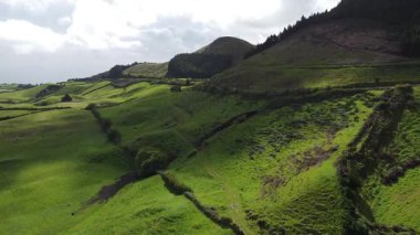 Sarp yeşil tepeleri ve Azores adalarının canlı otlaklarını saran çarpıcı bir hava manzarası. Bu manzarada el değmemiş doğanın dingin güzelliği sergileniyor. Yeşillik ve dolambaçlı yollar kırsal alanda uzanıyor..