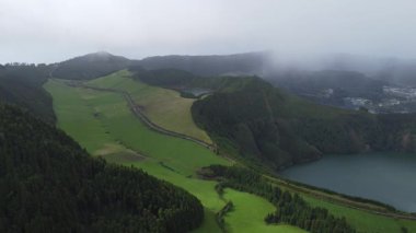 Azores adalarında bulunan yemyeşil çayırların ve dingin göllerin bulunduğu sisli bir vadinin nefes kesici hava manzarasını keşfedin..