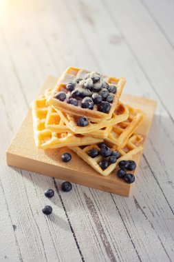 Sabahın köründe ahşap bir masada yaban mersinli Belçika waffle 'ı yığını