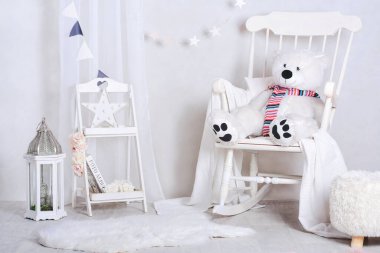 Sallanan sandalyesi ve doldurulmuş kocaman ayısı olan parlak, rahat çocuk odası.