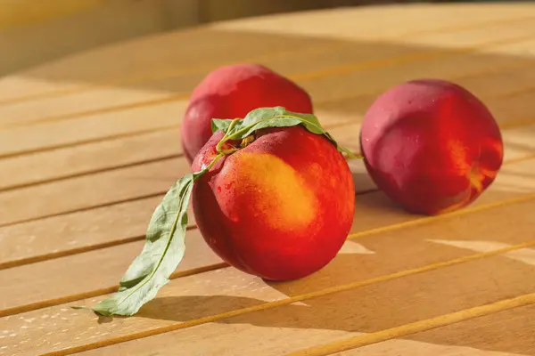 Masanın üzerinde taze nektarinler var.