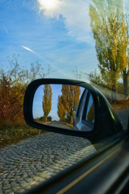 Sonbaharda eski bir kaldırım taşı yolda giden arabanın dikiz aynası.