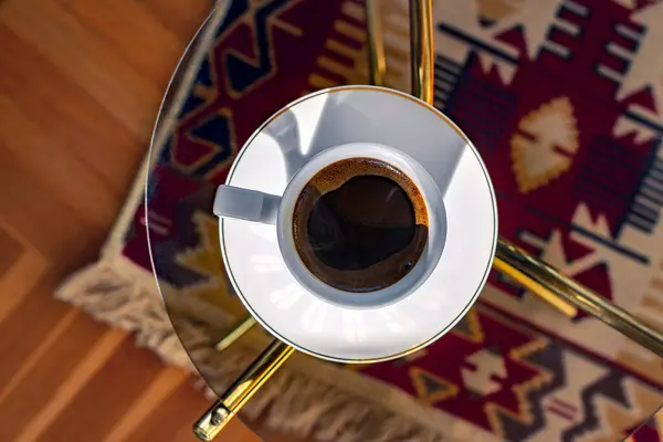 Beyaz porselen bir fincanda Türk kahvesine yakın plan, kilim desenli arka plan