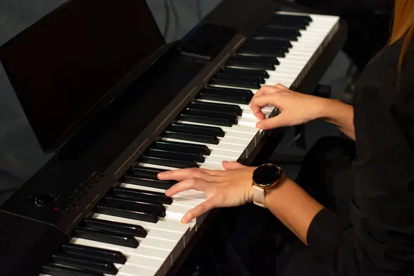 Konserde müzik çalan kadın elleri klavyede.