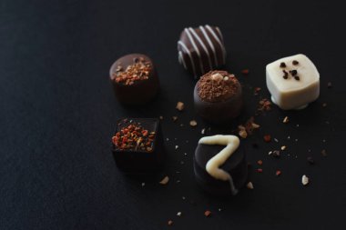 Koyu renkli tepside süslü çikolata çeşitleri.