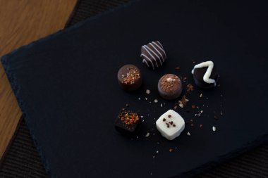 Masadaki siyah tabakta el yapımı çikolatalar.