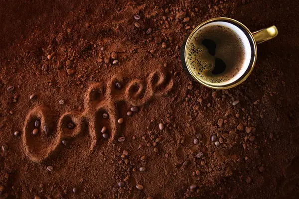 Kahve fincanı ve altın köpüklü kavrulmuş kahveden çapraz oyulmuş kelime 