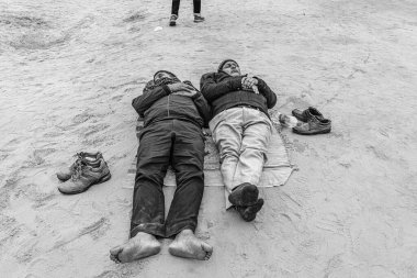 Two men pause beside the path, taking a brief respite amidst the spiritual hustle of Mahakumbh in Prayagraj. clipart