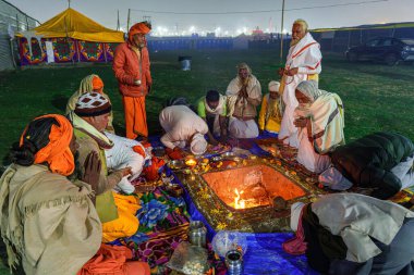 Digambar sadhus performing a sacred hawan around a blazing fire, offering prayers and chants amidst divine energy at Triveni Sangam, Prayagraj. clipart