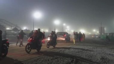 Prayagraj, Uttar Pradesh, Hindistan, 11 Ocak 2025. Seyyahlar, Mahakumbh 'un sisli yollarında, sakin bir akşamda kendilerini adamış bir şekilde yollarına devam ederler..