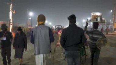 Prayagraj, Uttar Pradesh, Hindistan, 11 Ocak 2025. Alacakaranlıkta aydınlanmış Kumbh Mela sokaklarında hareketli bir kalabalık, inancın ve şenliğin özünü yakalıyor..