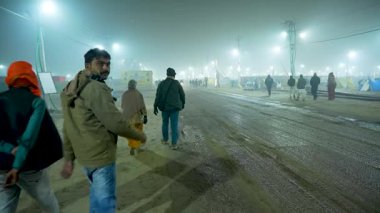 12 Ocak 2025, Prayagraj, uttar Pradesh, Hindistan. Bir kaç fanatik sessizce yürürken, yoğun bir sis gece caddesini kaplıyor..