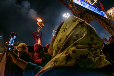 Varanasi, Uttar Pradesh, Hindistan, 26 Ocak 2024: Bir kadın saygı içinde duruyor, büyüleyici Ganga Aarti 'yi yakalıyor, geceyi aydınlatan kutsal alevler gibi..