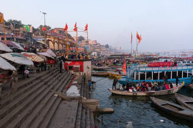 Varanasi, Uttar Pradesh, Hindistan, 26 Ocak 2024: Güneş ufuktan aşağı batar, Gangaz dalgalarının günün son altın ışıklarını yakaladığı Dashashwamedh Ghat üzerinde uzun gölgeler bırakır.