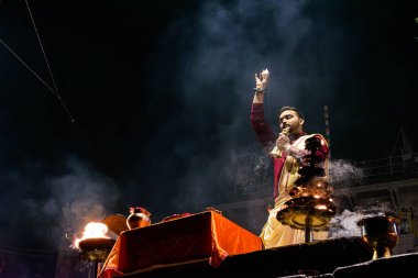 Varanasi, Uttar Pradesh, Hindistan, 26 Ocak 2024: Bir rahip Varanasi 'de aarti yaparken deniz kabuğu kabuğu tutuyor, kutsal alevler ghatları aydınlatırken, ibadetle ayakta duruyor.